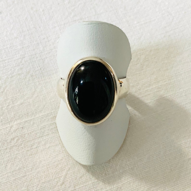 Op de afbeelding: Een zilveren ring met een zwarte ovale edelsteen.