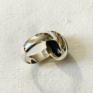 Op de afbeelding: Een zilveren ring met een zwarte ovale edelsteen. De ring is in een eenvoudige, elegante stijl.