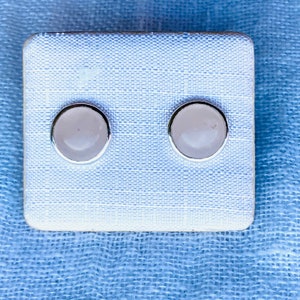 Op de afbeelding: Een paar zilveren oorbel studs met ronde witte stenen in het midden.