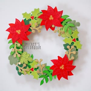 May include: A festive Christmas wreath featuring red poinsettias, green holly leaves, and gold glitter accents. The wreath has a circular shape and is decorated with various shades of green and gold. The text "Mickey's Decorator" is visible.