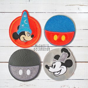 Puede incluir: Cuatro parches redondos bordados con Mickey Mouse en diferentes poses. Los parches son rojo, azul, gris y plateado. Mickey Mouse lleva un sombrero de mago azul en el parche rojo, un sombrero azul y rojo en el parche azul, un sombrero plateado en el parche plateado y un sombrero blanco y negro en el parche gris. El texto "Mickey's Decorator" est&aacute; impreso debajo de los parches.
