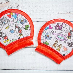 May include: Two red fabric Mickey Mouse ears with a white background featuring a variety of Disney characters and the text "Walt Disney World Disneyland".
