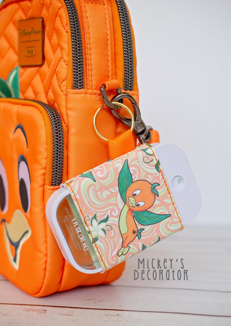 Puede incluir: Bolso bandolera naranja con una funda a juego con el dise&ntilde;o de Orange Bird. La funda, que contiene un pulverizador blanco, est&aacute; sujeta al bolso con un cierre dorado. El bolso tiene un patr&oacute;n acolchado y cierre de cremallera.