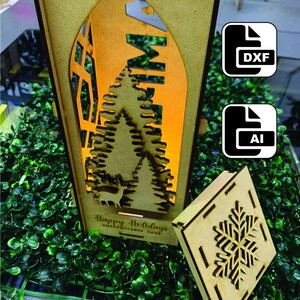 Puede incluir: Una linterna de Navidad de madera con un diseño recortado de un árbol de Navidad, un ciervo y la palabra "Merry". La linterna tiene una tapa extraíble con un diseño de copo de nieve. El texto "Happy Holidays Customizable Home" está impreso en la parte inferior de la linterna.