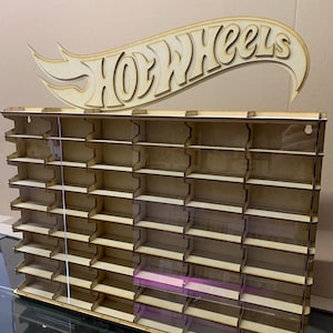 May include: Wooden Hot Wheels display shelf with a cutout Hot Wheels logo. The shelf has 48 slots for displaying Hot Wheels cars. The shelf is made of wood and has a clear acrylic front.