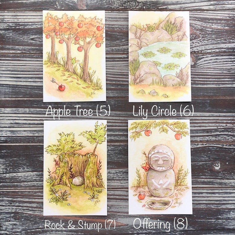 Op de afbeelding: Vier aquarel illustraties op witte kaarten. Linksboven appelbomen met rode appels en de tekst "Apple Tree (5)". Rechtsboven een vijver met waterlelies en de tekst "Lily Circle (6)". Linksonder een rots en een stronk met de tekst "Rock & Stump (7)". Rechtsonder een stenen beeld met de tekst "Offering (8)".
