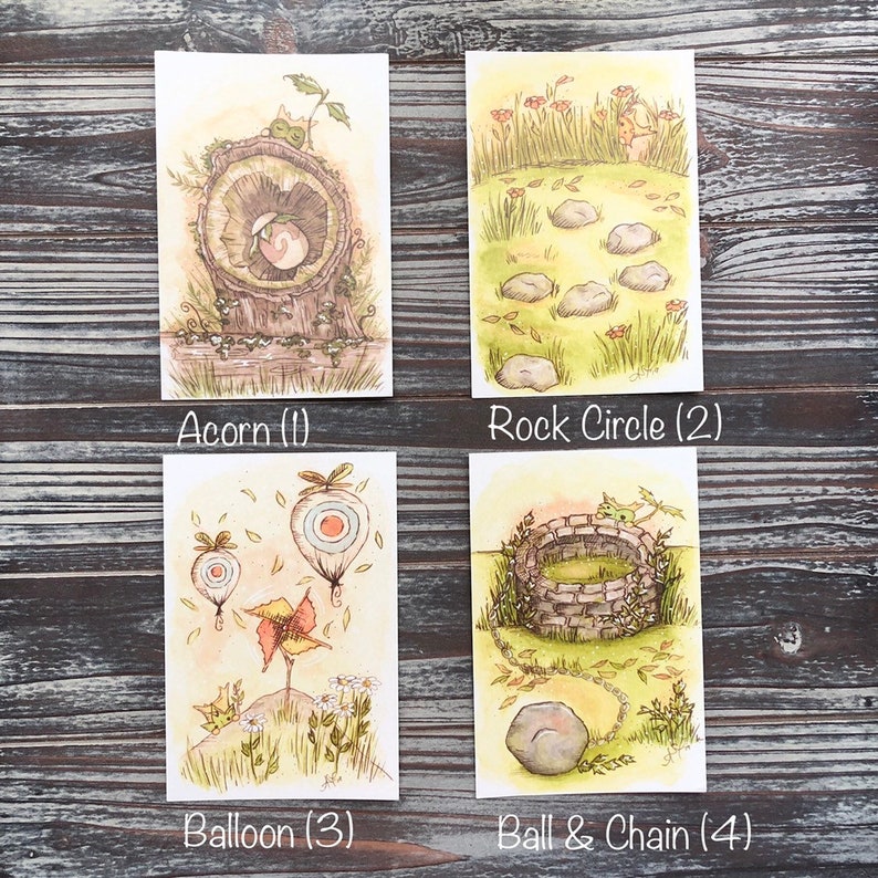 Op de afbeelding: Vier aquarel illustraties op rechthoekige kaarten. De illustraties tonen een eikel, een steencirkel, ballonnen en een bal en ketting. Elke kaart heeft een titel onderaan: Acorn (1), Rock Circle (2), Balloon (3) en Ball & Chain (4).