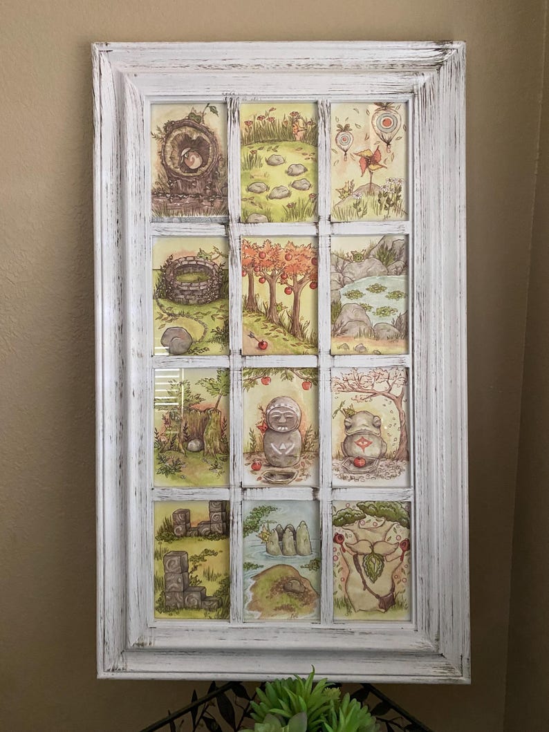 Op de afbeelding: Een wit omkaderd kunstwerk met twaalf kleine, ge&iuml;llustreerde sc&egrave;nes. De sc&egrave;nes tonen grillige landschappen met bomen, rotsen en figuren. Het kunstwerk heeft een verweerde, vintage uitstraling, met een wit geschilderde lijst. De illustraties zijn in zachte, aardse tinten.