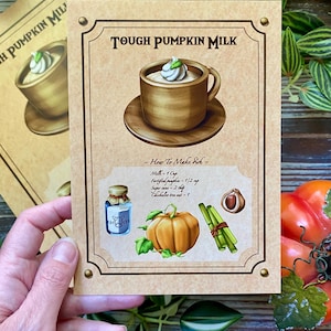 Op de afbeelding: Een vintage receptkaart voor "Tough Pumpkin Milk" met een gedetailleerde illustratie van een kopje van het drankje, ingredi&euml;nten en instructies. De kaart is bruin met decoratieve randen en tekst.