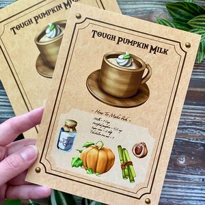 Op de afbeelding: Twee kaarten met de tekst "TOUGH PUMPKIN MILK" en een illustratie van een drankje in een houten mok met slagroom. E&eacute;n kaart toont een recept met een pompoen, kruiden en een fles melk.