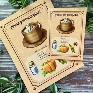 Op de afbeelding: Twee bruine papieren prints met de tekst "TOUGH PUMPKIN MILK". E&eacute;n print toont een kop melk met slagroom, de andere een pompoen, kruiden en een fles. De prints liggen op een houten oppervlak.