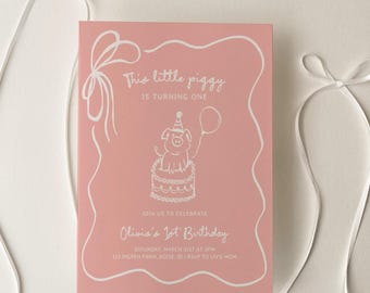 May include: A pink birthday invitation with white text and a pig illustration. The invitation reads "This little piggy is turning one" and includes event details. White ribbons are arranged around the invitation on a white surface.