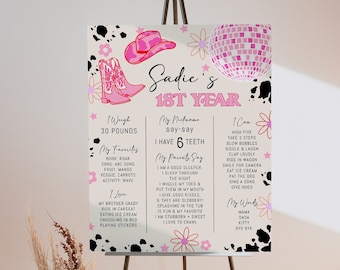 May include: A pink and white printable poster with black cow spots. The poster celebrates a baby girl's first birthday with the name Sadie. The poster includes details about the baby's weight, favorite activities, and words she says.