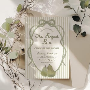 Peut inclure: Invitation de fête prénuptiale sur le thème de la poire. L'invitation présente le texte "The Perfect Pair" dans une écriture élégante, ainsi que les détails de l'événement. Le design comprend une palette de couleurs vert clair avec des rayures verticales et des illustrations de poires.