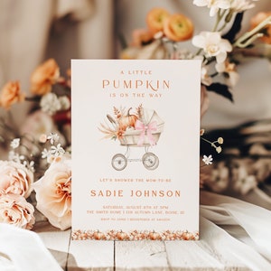 Op de afbeelding: Een uitnodiging voor een babyshower met de tekst "A Little Pumpkin Is On The Way". De uitnodiging bevat een aquarel illustratie van een vintage kinderwagen met pompoenen en bloemaccenten. De uitnodiging bevat ook de naam "Sadie Johnson" en evenementdetails.