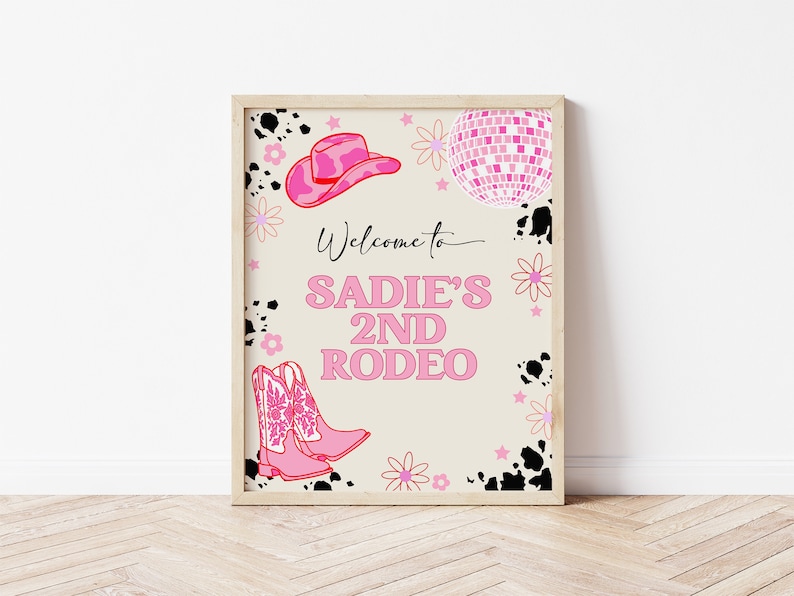 May include: A pink and white welcome sign for a rodeo party. The sign says "Welcome to Sadie's 2nd Rodeo". There are pink cowboy boots, a pink cowboy hat, and a pink disco ball on the sign.