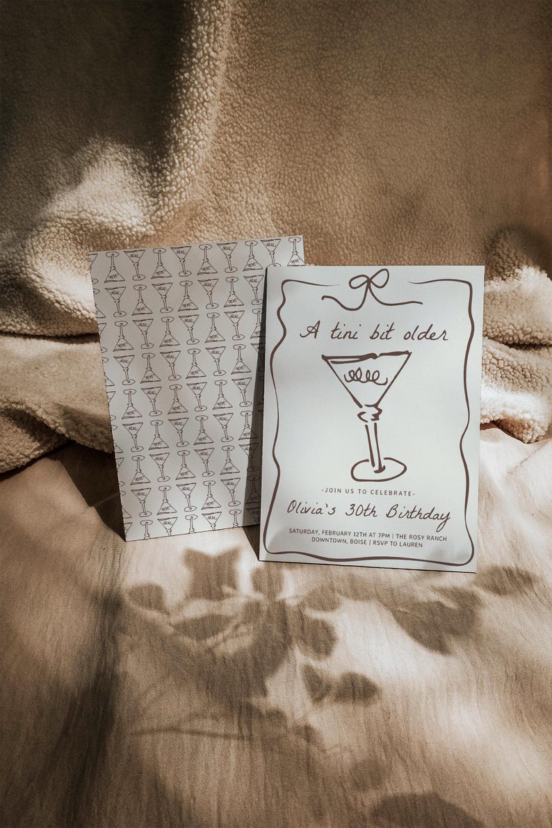 Op de afbeelding: Een witte uitnodigingskaart met een bruine illustratie van een martini-glas en de tekst "A tini bit older". De tekst "Olivia's 30th Birthday" staat onder de illustratie. De uitnodiging geeft de datum, tijd en locatie van het evenement aan.