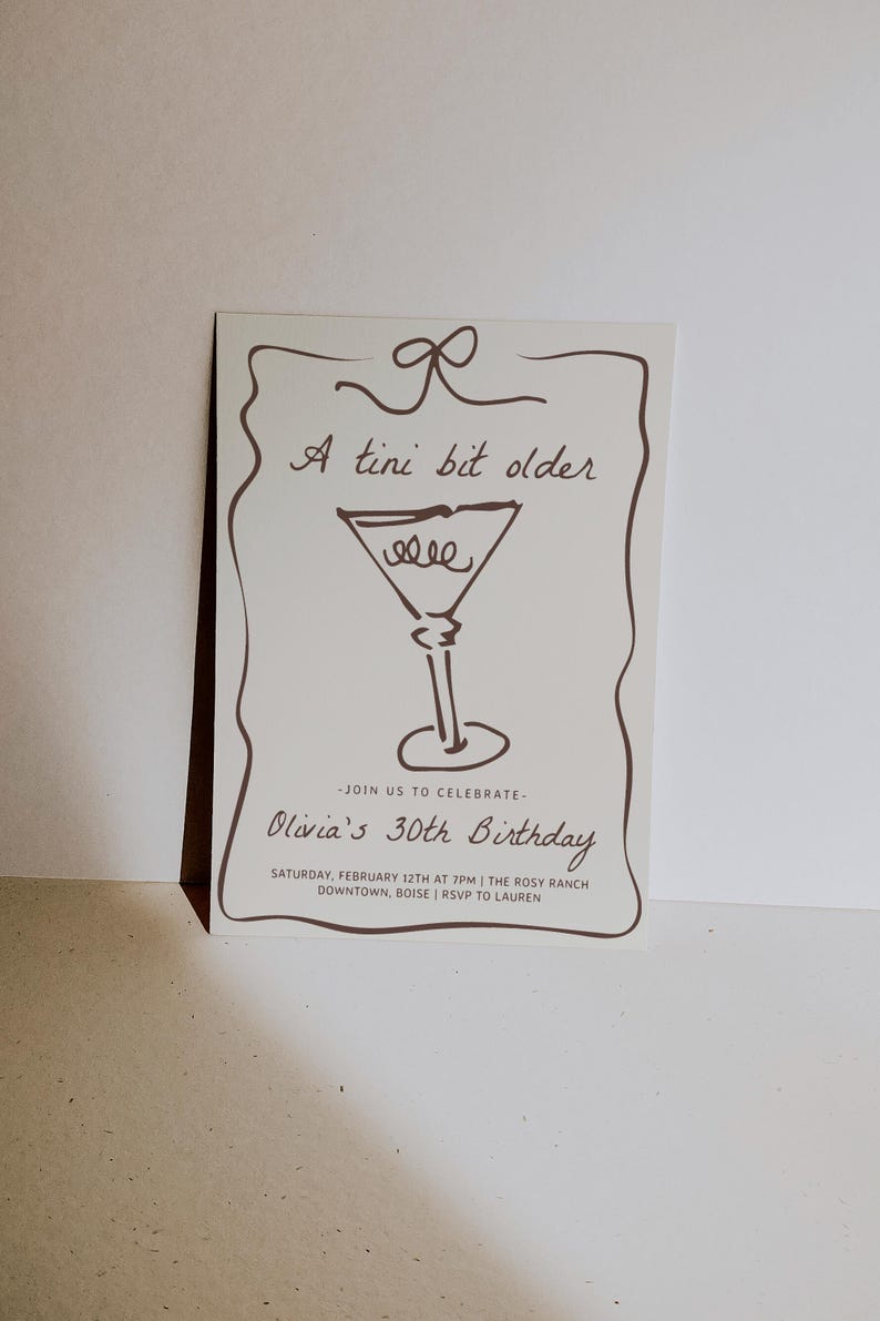 Op de afbeelding: Een witte uitnodigingskaart met bruine tekst en een tekening van een martini-glas. De tekst luidt "A tini bit older" en "Olivia's 30th Birthday". De uitnodiging beschrijft een feest op zaterdag 12 februari om 19:00 uur in The Rosy Ranch in Downtown, Boise. RSVP aan Lauren.