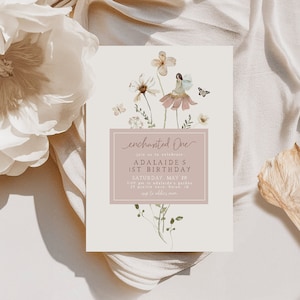 Può includere: Un invito rosa chiaro e bianco con un design floreale e un'illustrazione di una fata. Il testo recita "enchanted One" e "Join us to celebrate ADALAIDE'S 1ST BIRTHDAY, SATURDAY, MAY 20, 3:00 pm at ADALAIDE'S GARDEN, 21 PRAIRIE, BOISE, ID"