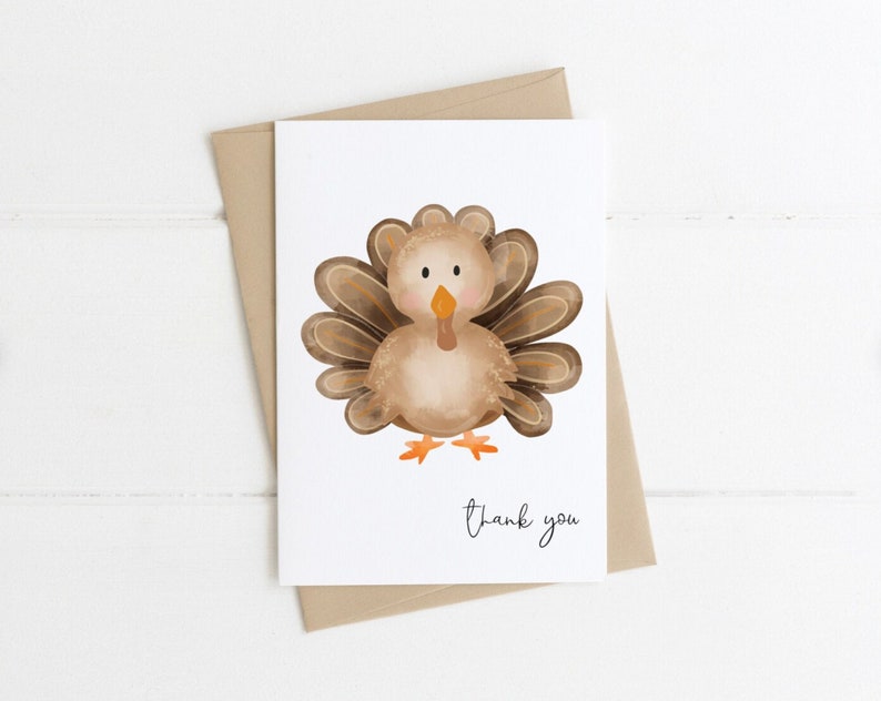 K&ouml;nnte beinhalten: Eine wei&szlig;e Gru&szlig;karte mit einer Aquarellillustration einer Truthahn. Der Truthahn ist braun, beige und orange, mit einem F&auml;cher aus Federn. Die Worte "thank you" sind in einer Schriftart unter dem Truthahn geschrieben. Die Karte liegt auf einem braunen Umschlag.