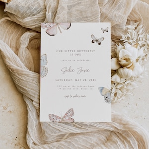 May include: A white invitation card with a pink and blue butterfly design. The text on the card reads "Our little butterfly is one. Join us to celebrate - Sadie Jane. Saturday, May 26, 2025. 3:00 pm at the Johnson home, 29 Prairie Cove, Boise, ID. RSVP to Sadie's Mom."