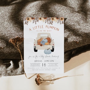 Pu&ograve; includere: Invito per baby shower con un'illustrazione ad acquerello di un camioncino vintage pieno di zucche. Il testo recita "A Little Pumpkin is on the Way" e include il nome Abigail Jameson, la data e l'ora.