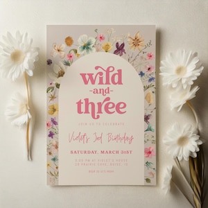 Peut inclure: Une invitation d'anniversaire rose et blanche avec une bordure florale et le texte "wild -and- three" et "Violet's 3rd Birthday". L'invitation comprend également la date, l'heure et le lieu de la fête.