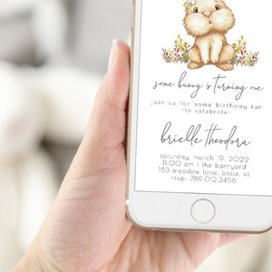 May include: A digital invitation for a first birthday party with a cute cartoon bunny illustration. The invitation says "some bunny is turning one" and includes the name "brielle theodora", the date "saturday, march 19, 2022", the time "11:00 am", the location "the barnyard, 153 meadow lane, boise, id", and the RSVP number "789.012.3456".