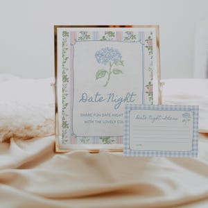 May include: A framed print with the words "Date Night" and a blue hydrangea illustration. A smaller card with "Date Night Ideas" is also visible. The design features a floral border and a soft color palette.
