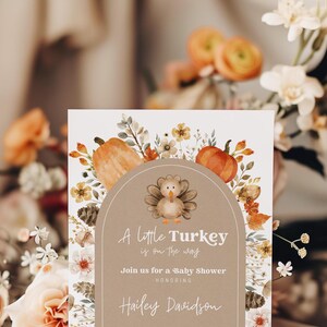Puede incluir: Una invitaci&oacute;n a un baby shower con un dise&ntilde;o de acuarela. La invitaci&oacute;n presenta una ilustraci&oacute;n de pavo, calabazas y elementos florales. El texto dice "A little Turkey is on the way" e invita a los invitados a un baby shower en honor a Hailey Davidson.