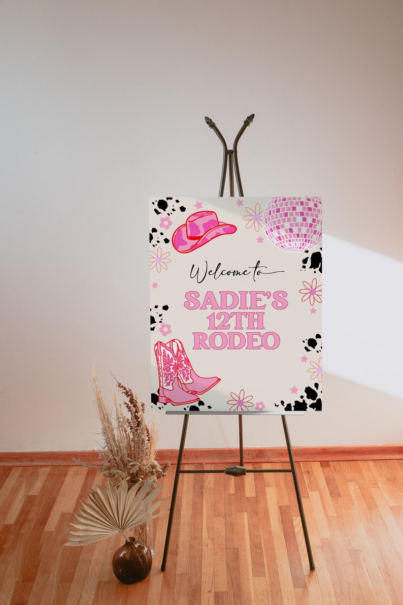 May include: Welcome to Sadie's 12th Rodeo sign with pink cowboy boots, a pink cowboy hat, and a pink disco ball on a white background with black cow spots and pink flowers.
