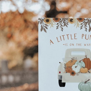Op de afbeelding: Een lichtblauwe kaart met de tekst "A LITTLE PUMPKIN IS ON THE WAY" en een tekening van een vintage truck vol pompoenen. De bovenkant van de kaart heeft een bloemenontwerp met zonnebloemen en bladeren.