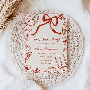 May include: A cream-coloured baby shower invitation featuring red illustrations of pizza slices, grapes, and wine glasses. The text "Slice, Slice, Baby" is displayed, along with event details and the name Olivia Anderson.