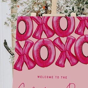 May include: Pink welcome sign with a pattern of pink XOXO balloons. The sign says "Welcome to the ..."