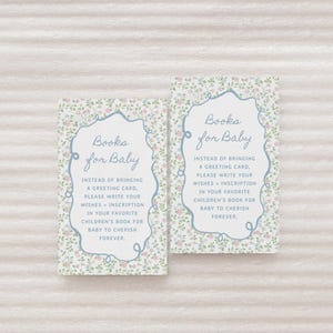 以下が含まれることがあります： 花柄と「Books for Baby」の文字が入ったベビーシャワーカード2枚。カードには水色の縁取りがあり、「グリーティングカードの代わりに、あなたの願い+お気に入りの子供向けの本への碑文を書いて、赤ちゃんが永遠に大切にできるようにしてください」と書かれています。