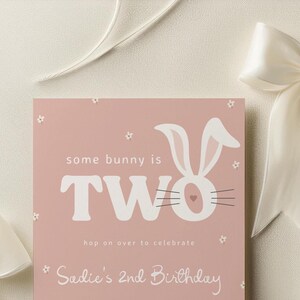 Puede incluir: Tarjeta de cumplea&ntilde;os rosa con una ilustraci&oacute;n de conejo blanco y el texto "some bunny is TWO hop on over to celebrate Sadie's 2nd Birthday".