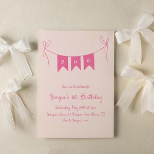 May include: Pink and white birthday party invitation with the text "Join us to celebrate Georgia's 1st Birthday" and details about the party. The invitation is decorated with white bows.