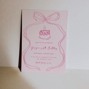 May include: Pink birthday invitation featuring a hand-drawn illustration of a cake with a candle and a bow. The text reads "Join us to celebrate Georgia's 6th Birthday, Saturday, August 21st, 5:00 PM at Georgia's House, 129 Ribbon Lane, Love Georgia's Mum."
