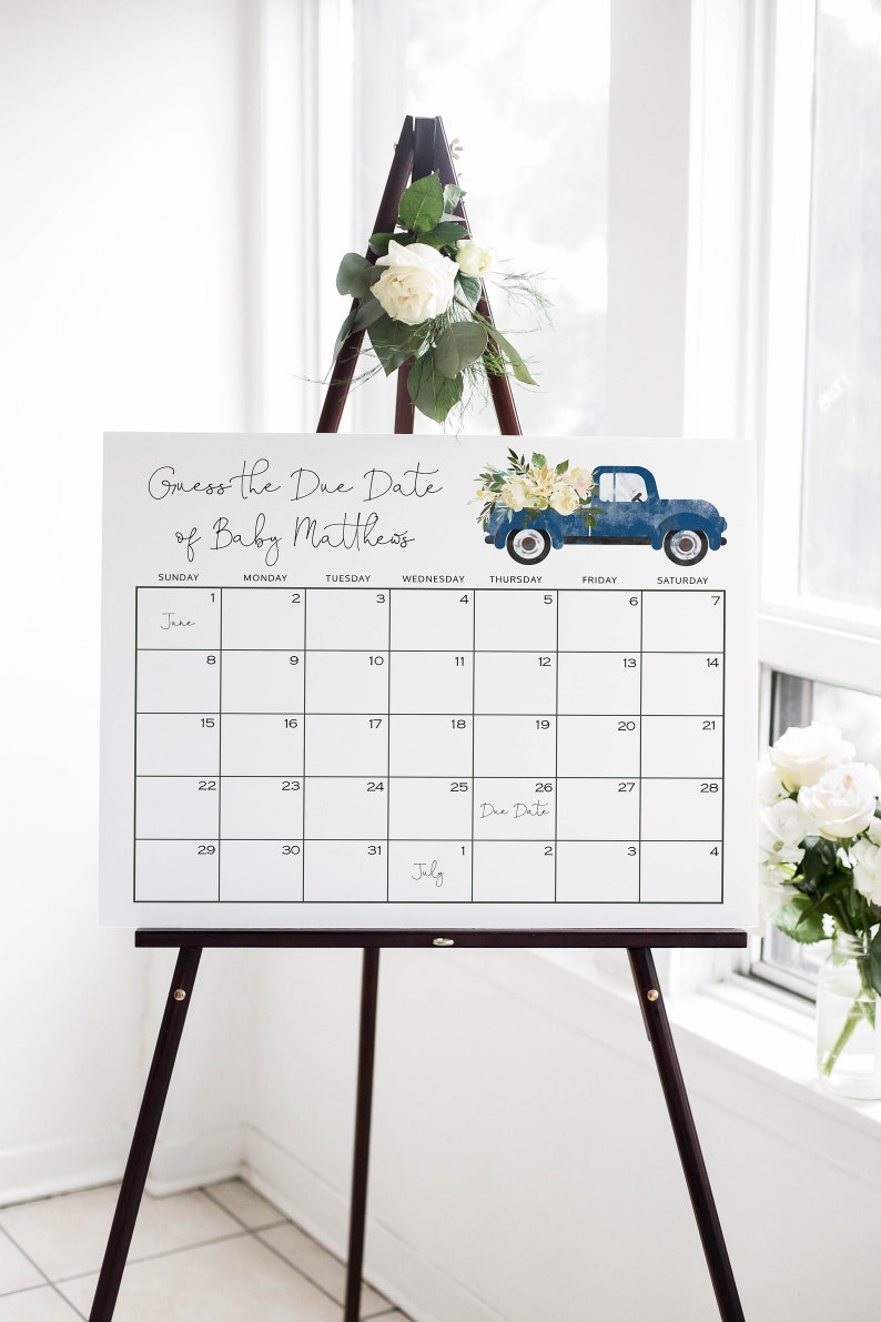 May include: A white calendar with a blue truck graphic and floral accents. The calendar is set up for June and July with the text "Guess the Due Date of Baby Matthews" at the top. The due date is marked on the calendar as July 26th.