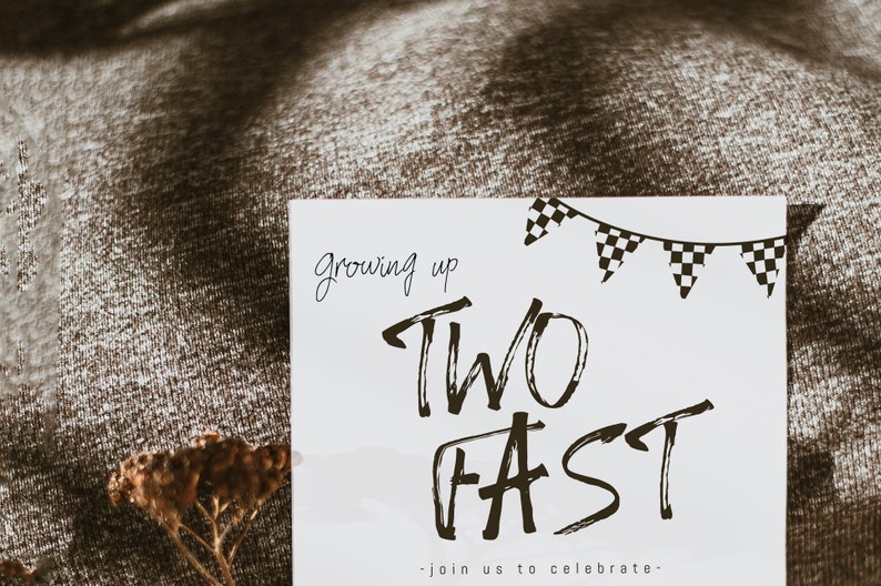 May include: A white card with black text that reads "Growing up Two Fast - Join us to celebrate."  The card has a black and white checkered banner at the top.