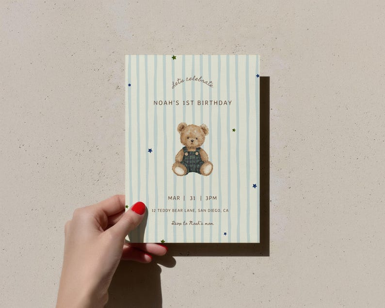 May include: An invitation card with a light blue and white striped design, featuring a teddy bear illustration and the text "Let's celebrate" and "Noah's 1st Birthday". The card includes event details and is held by a hand.
