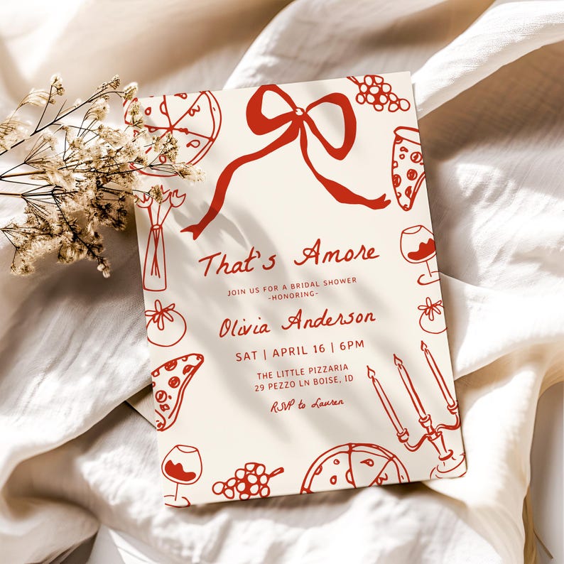 May include: A red and white bridal shower invitation with the text "That's Amore" and "Olivia Anderson". The invitation features a red bow, pizza slices, wine glasses, grapes, and candles.