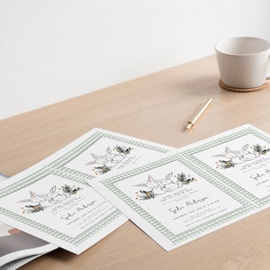 May include: Four white cards with a green and white checkered border. Each card features a drawing of two bunnies with a floral design and the text "We're having a baby shower!" and "[Name] Address".