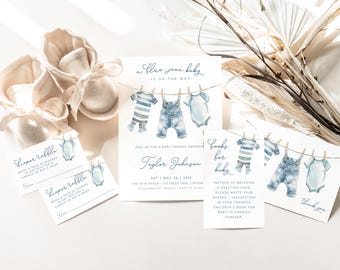 May include: A baby shower invitation with a blue jean theme. The invitation features a watercolor illustration of three baby clothes hanging on a clothesline. The text on the invitation reads "A blue jean baby is on the way."  The invitation also includes the name "Tayler Johasen" and the date and time of the baby shower. There are also two cards that say "Diaper Raffle" and one card that says "Books for Baby".