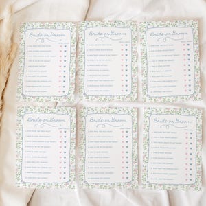 May include: Six floral-bordered "Bride or Groom" game cards. Each card features a list of questions with heart-shaped check boxes. The cards have a light blue border and floral accents in pink and green.