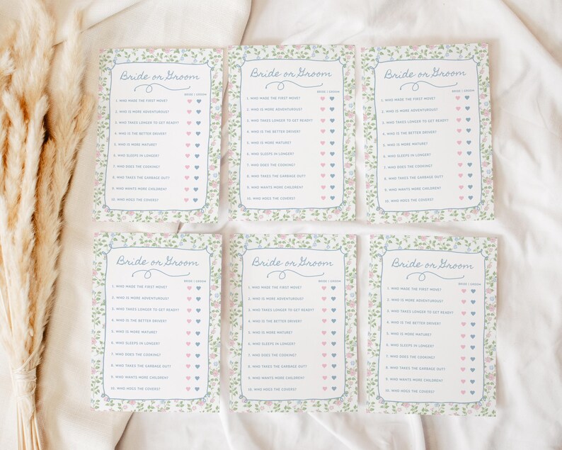May include: Six floral-bordered "Bride or Groom" game cards. Each card features a list of questions with heart-shaped check boxes. The cards have a light blue border and floral accents in pink and green.