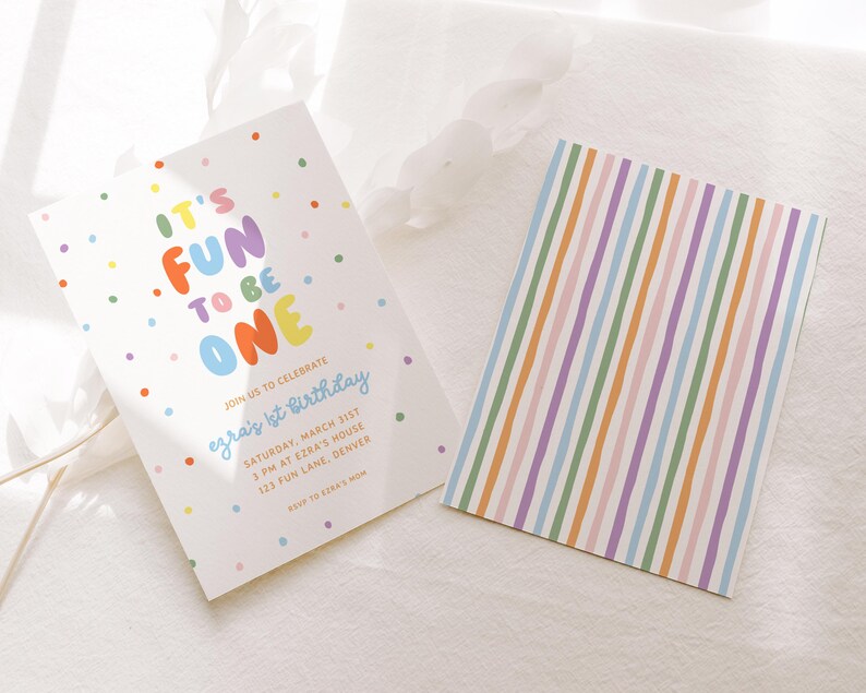 May include: Two white cards. One features the text "IT'S FUN TO BE ONE" in colorful letters, with confetti dots. The other card has vertical stripes in pastel colors. The text on the first card reads "Join us to celebrate Ezra's 1st Birthday".