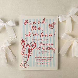 May include: An invitation for a first birthday celebration with the text "Pinch Me, I'm One!" in red script. The invitation features a red lobster illustration and is surrounded by white satin bows. The invitation is for Rowan's 1st Birthday.