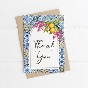 Puede incluir: Una tarjeta de agradecimiento con un patr&oacute;n de azulejos azules y blancos, un dise&ntilde;o floral con flores rosas y limones amarillos, y el texto "Gracias".