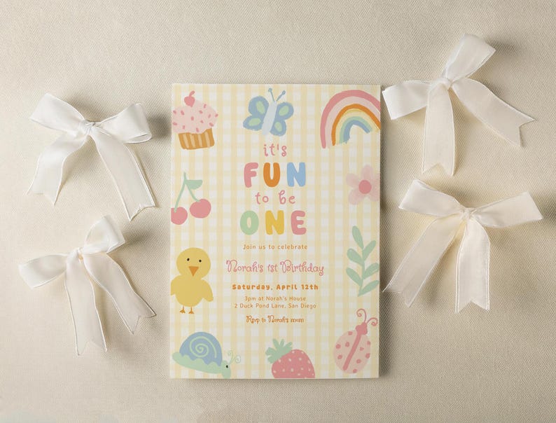 May include: A birthday invitation with the text "it's FUN to be ONE" on a yellow gingham background. The invitation is decorated with colorful illustrations of a cupcake, butterfly, rainbow, and other cute graphics. White satin bows are scattered around the invitation.